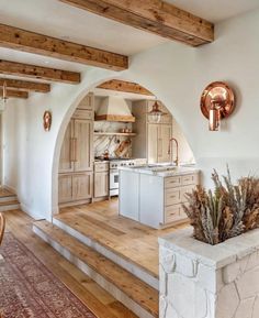 a kitchen with wooden floors and an archway leading to the dining room area is shown