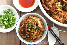 two bowls filled with food next to some chopsticks and sauce on a table