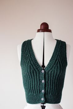 a mannequin wearing a green sweater vest with buttons on the front and back