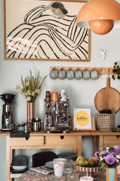 a dining room table with coffee cups and other items on it next to a painting