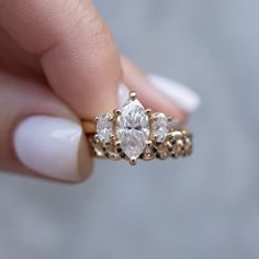 a woman's hand holding an engagement ring with three stones on it and the center diamond