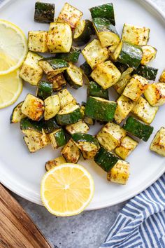 grilled zucchini on a white plate with lemon wedges next to it