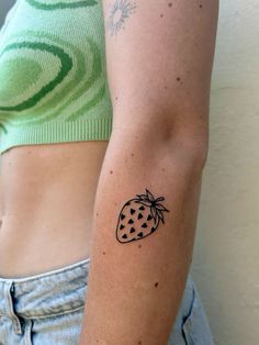 a woman with a tattoo on her arm holding a strawberries in one hand and a banana in the other