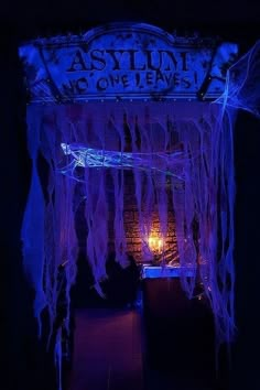 the entrance to an abandoned building decorated in purple and blue lights, with icicles hanging from it's roof