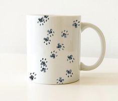 a white coffee mug with blue and black paw prints on it, sitting on a table