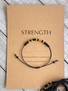 "Strength" Morse Code Bracelet. A daily reminder for you to know you are strong and to keep pushing through!  This bracelet is made with high quality, black waxed cotton cord - which is durable and lightweight. Beautiful black and gold glass seed beads are used for your message. Or choose other color combo at checkout.  Bracelet is adjustable with a sliding knot that fits most wrist sizes. Bracelet comes shipped with card stock packaging as shown.  Want a customized morse code bracelet? Message Morse Code Bracelet Messages, Black Bead Bracelet, Morse Code Bracelets, Affirmation Bracelets, Bracelet Message, Crochet Bracelet Pattern, Beaded Braclets, Gift For Coworker, Bracelets With Meaning