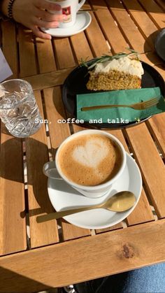 a cup of coffee sitting on top of a wooden table next to a slice of cake