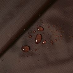 drops of water are on the surface of a brown fabric, which is slightly visible