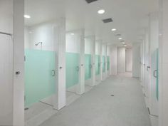 an empty bathroom with white walls and green glass partitions on the wall to separate it from the rest of the room