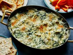 a casserole dish with spinach and cheese in it next to crackers