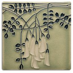 an artistic metal art piece with flowers and leaves hanging from it's sides on a wall