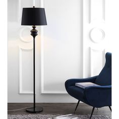 a blue chair sitting in front of a lamp on top of a wooden floor next to a white wall