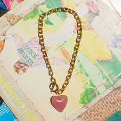 a heart shaped necklace on a chain with a book in the backgrouf