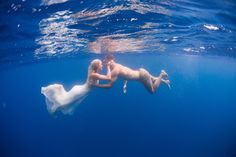 a man and woman are swimming in the ocean with their backs to each other as they hold hands