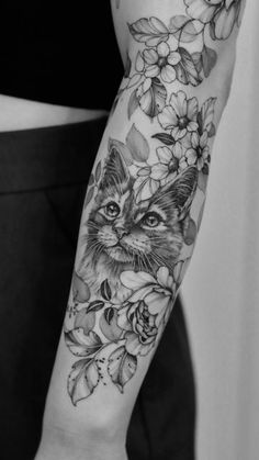 a black and white photo of a cat with flowers on it's arm,