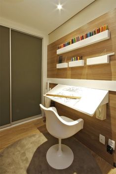 a white chair sitting in front of a desk with bookshelves on the wall