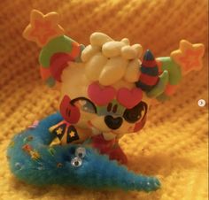 a close up of a small toy on a yellow blanket with stars and clown hats