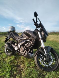 a motorcycle parked in the grass with a helmet on it's back end,