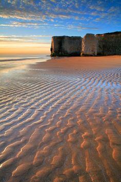 the beach is covered in sand and has two large rock formations on top of it