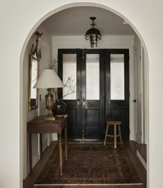 an archway leading into a room with two chairs and a rug on the floor in front of it