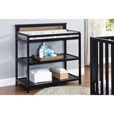 a baby crib with three shelves and two baskets on the bottom, next to a white rug