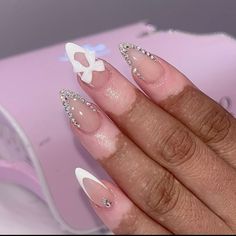 Short almond acrylic nails with white French tip and white bow charm with rhinestone bling French tips Almond French With Rhinestones, Almond Nails Bling, White Almond French Tip Nails With Gems, Almond French Tips With Gems, Bling Almond Nails Rhinestones, Rhinestone French Tip, Almond Bling Nails, Diamond French Tip Nails, Bling Almond Nails