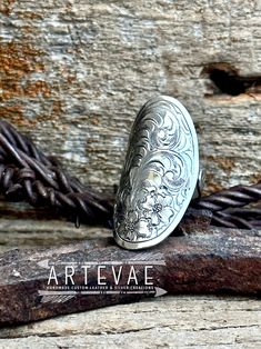 a silver ring sitting on top of a piece of wood next to a barbed wire