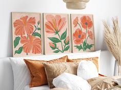 three orange flowers are displayed on the wall above a bed with white sheets and pillows