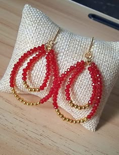 red beaded hoop earrings sitting on top of a pillow