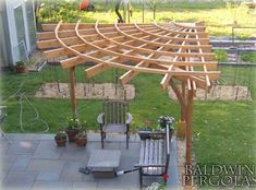 a wooden pergolan sitting on top of a patio next to a garden area