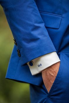 a man in a blue suit with his hand on his lapel and wearing a white cuff