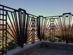 an iron railing on top of a building with trees and mountains in the back ground