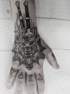 a hand that has a tattoo on it with an animal head and two swords in the middle