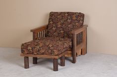 a wooden chair with a floral upholstered seat and foot rest in front of a wall