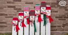 snowmen made out of wooden slats with red hats and scarfs on them