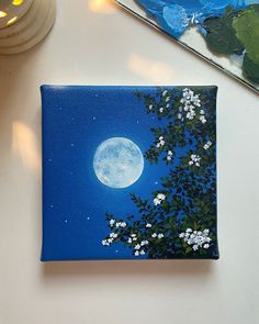 a painting on a white table with a blue sky and full moon