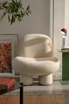 a white chair sitting on top of a table next to a potted plant in a living room