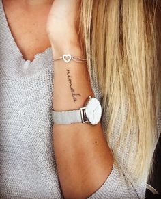 a woman's wrist with a watch on it and the word love written in cursive writing