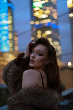 a woman in a fur coat is posing for the camera with her hand on her head