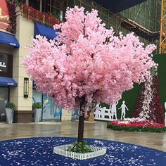 a tree with pink flowers is in the middle of a blue carpeted area at an indoor mall