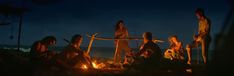 a group of people sitting around a campfire at night with torches in their hands