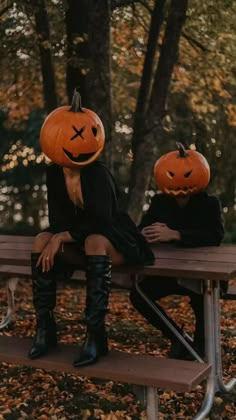 two people sitting on a bench with pumpkins in their heads and one person wearing boots