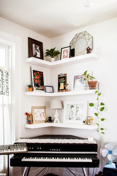 a piano is sitting in front of some shelves with pictures on it, and a fan