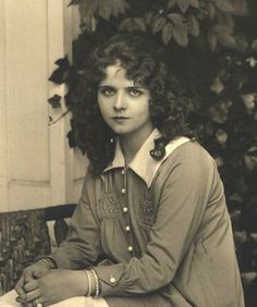 an old black and white photo of a woman sitting on a bench