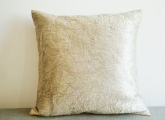 a white pillow sitting on top of a wooden table next to a wall with a plant