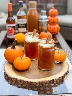 two mugs filled with liquid sitting on top of a wooden table next to pumpkins