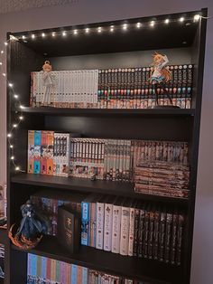 a bookshelf filled with lots of books next to a wall covered in lights