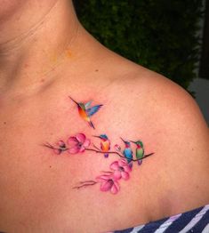 a woman's chest with flowers and hummingbirds on the top left side of her neck