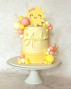 a yellow and pink birthday cake with balloons on the top that say anemu