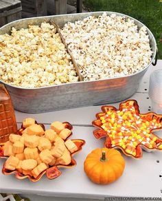 a table topped with lots of food next to a metal pan filled with popcorn and candy